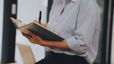 Genç bir iş kadını, bir iş ve finans temasını yansıtan çağdaş ofis ortamında çalışmalarına odaklanmış..