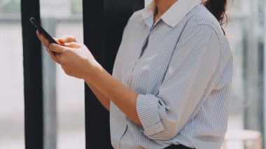 Şık bir ofiste cep telefonu kullanan genç bir iş kadını, hızlı iş ve finans dünyasını yansıtıyor..