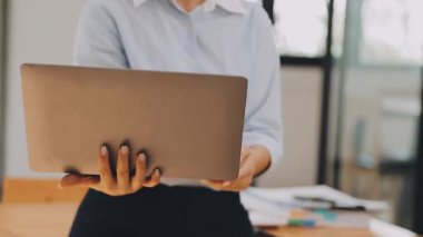 Genç bir iş kadını, bir iş ve finans temasını yansıtan çağdaş ofis ortamında çalışmalarına odaklanmış..