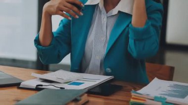 Modern ofiste belgelerle çalışan genç iş kadını, hızlı iş ve finans dünyasını yansıtıyor..