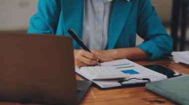 Modern ofiste belgelerle çalışan genç iş kadını, hızlı iş ve finans dünyasını yansıtıyor..