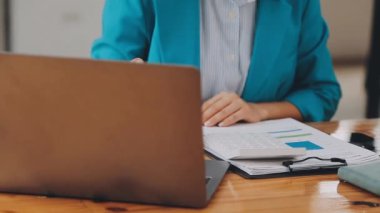 Modern ofiste belgelerle çalışan genç iş kadını, hızlı iş ve finans dünyasını yansıtıyor..