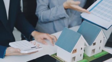 Mimarlar modern bir ofiste bir yapı modeli üzerinde işbirliği yaparken, tasarımcılar inşaat, geliştirme, kentsel planlama, proje yönetimi ve yaratıcı fikirlerle ilgili mimari kavramlar geliştirmeye odaklanıyor.