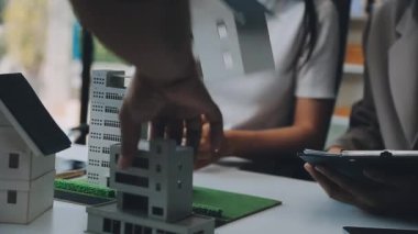 Mimarlar modern ofiste bir bina modeli üzerinde çalışıyorlar. Tasarımcı mimariyi geliştiriyor. İnşaat, geliştirme, kentsel planlama, proje yönetimi ve yaratıcı fikir.