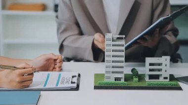 Mimarlar modern bir ofiste bir yapı modeli üzerinde işbirliği yaparken, tasarımcılar inşaat, geliştirme, kentsel planlama, proje yönetimi ve yaratıcı fikirlerle ilgili mimari kavramlar geliştirmeye odaklanıyor.