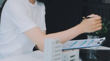 Mimarlar modern bir ofiste bir yapı modeli üzerinde işbirliği yaparken, tasarımcılar inşaat, geliştirme, kentsel planlama, proje yönetimi ve yaratıcı fikirlerle ilgili mimari kavramlar geliştirmeye odaklanıyor.
