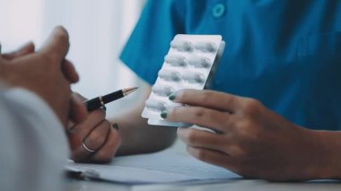 Beyaz önlüklü genç doktor elinde haplar ve elinde hastayla
