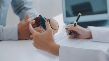 Doktor kalbi yaşlı bir hastaya detaylı bir kalp modeli kullanarak yapısını ve işlevini anlatıyor..