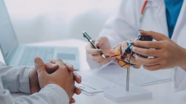 Doktor kalbi yaşlı bir hastaya detaylı bir kalp modeli kullanarak yapısını ve işlevini anlatıyor..