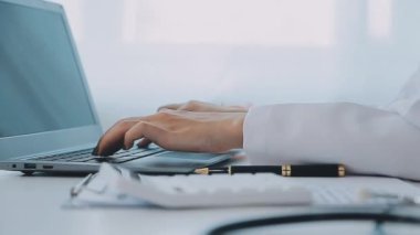 Yakın çekim, klinikte dizüstü bilgisayarla çalışan kadın doktor görüntüsü. Bilgisayar ekranında steteskop kullanan bir sağlık görevlisi. modern tıp bürosu