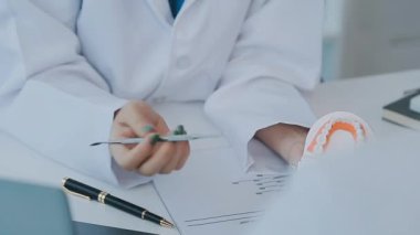 Dişçi, modern klinikteki bir hastayla diş sorunlarını tartışıyor.