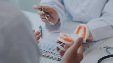 Dişçi, modern klinikteki bir hastayla diş sorunlarını tartışıyor.