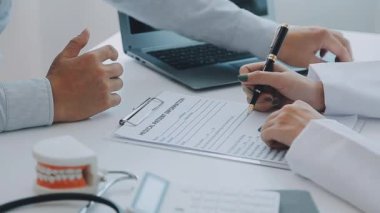 Dişçi, modern klinikteki bir hastayla diş sorunlarını tartışıyor.