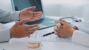 Dişçi, modern klinikteki bir hastayla diş sorunlarını tartışıyor.