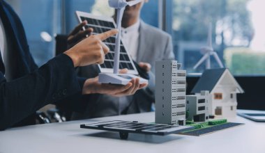 İki Genç Mühendis Güneş Hücresi Kurulum Toplantısı ve İş Tartışması Uzmanı. Ofis Odası 'nda Fabrika İnşaat Planlı Çatı Üzerine Güneş Fotovoltaik Panelleri Kurmayı Planlıyorum.