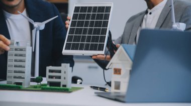 İki Genç Mühendis Güneş Hücresi Kurulum Toplantısı ve İş Tartışması Uzmanı. Ofis Odası 'nda Fabrika İnşaat Planlı Çatı Üzerine Güneş Fotovoltaik Panelleri Kurmayı Planlıyorum.