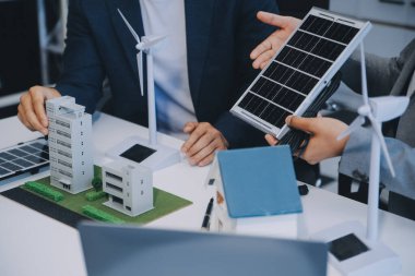 İki Genç Mühendis Güneş Hücresi Kurulum Toplantısı ve İş Tartışması Uzmanı. Ofis Odası 'nda Fabrika İnşaat Planlı Çatı Üzerine Güneş Fotovoltaik Panelleri Kurmayı Planlıyorum.