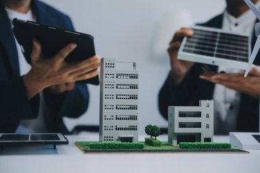 İki Genç Mühendis Güneş Hücresi Kurulum Toplantısı ve İş Tartışması Uzmanı. Ofis Odası 'nda Fabrika İnşaat Planlı Çatı Üzerine Güneş Fotovoltaik Panelleri Kurmayı Planlıyorum.