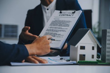 Emlakçı ev satın alma anlaşmasının şartları hakkında konuştu ve müşteriden sözleşmeyi yasal hale getirmek için belgeleri imzalamasını istedi, ev satışları ve ev sigortası kavramı.