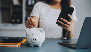 Genç Asyalı kadın emeklilik için para biriktiriyordu. Kumbaradan para biriktiriyordu ve defter, tasarruf konsepti gibi notlar alıyordu..