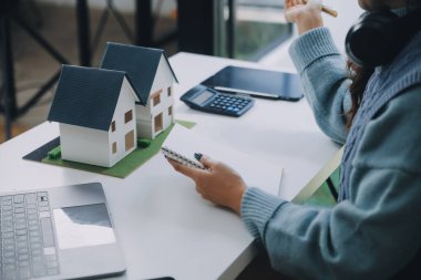 Emlakçı ve müşteri satın alma, sigorta ya da kredi alma ya da emlak ya da mülkiyet sözleşmesi hakkında tartışıyorlar.