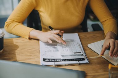 Akıllı telefon tutan genç bir kadın, ödeme başarısını gösteren bir tablet ve sarı paket kutusu olan kredi kartını ofiste online alışveriş kavramı olarak gösteriyor.