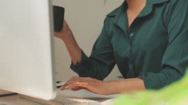 Genç Asyalı iş kadını modern ofis ortamında masa bilgisayarında çalışıyor.