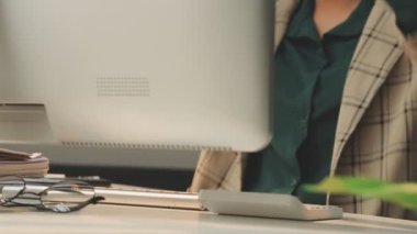 Genç Asyalı iş kadını modern ofis ortamında masa bilgisayarında çalışıyor.