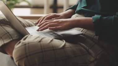 Genç Asyalı iş kadını, modern ofis ortamında dizüstü bilgisayarına odaklanıyor