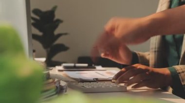 Ofiste hesap makinesi kullanan Asyalı işkadını mali rapor veya iş planı yatırımı, finans analizi kavramını analiz ederken.