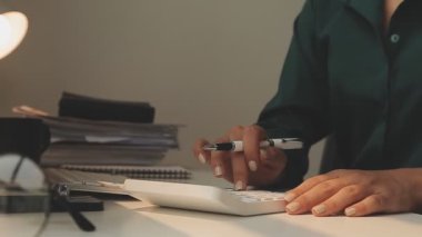 Ofiste hesap makinesi kullanan Asyalı işkadını mali rapor veya iş planı yatırımı, finans analizi kavramını analiz ederken.