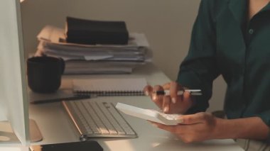 Ofiste hesap makinesi kullanan Asyalı işkadını mali rapor veya iş planı yatırımı, finans analizi kavramını analiz ederken.