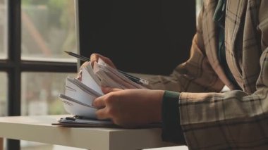 Ofisteki çalışma masasında bilgisayarı ve belgeleri olan bir iş kadını.