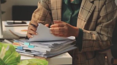 Ofisteki çalışma masasında bilgisayarı ve belgeleri olan bir iş kadını.