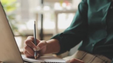 Not defterine dizüstü bilgisayarı olan bir kadın.