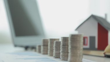 Evin modeli, madeni paralar ve dizüstü bilgisayarlar masada, yakın plan -