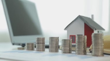 Evin modeli, madeni paralar ve dizüstü bilgisayarlar masada, yakın plan -