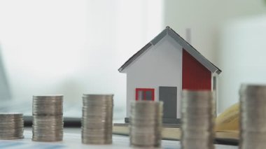Evin modeli, madeni paralar ve dizüstü bilgisayarlar masada, yakın plan -