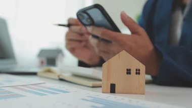 İş adamı hesap makinesi üzerinde çalışıyor. Ofiste ev modeli olan bir laptop..