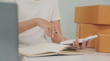 Online alışveriş ve online teslimat. Akıllı telefon kullanan ve kağıda yazı yazan kadın.