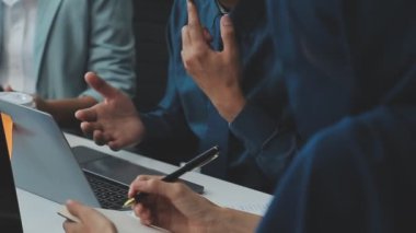 Bir takım şık bir ofiste büyük bir masa etrafında fikirler üretir.