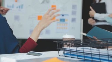 Genç iş uzmanlarından oluşan canlı bir ekip, son teknoloji ürünü bir ofiste etkili bir şekilde iş birliği yaparak finansal stratejiler ve ilkeler sergiliyor.