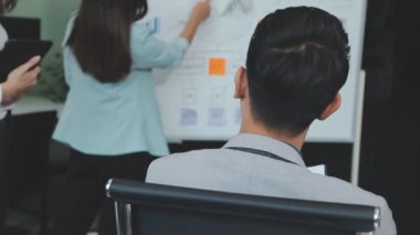 Genç iş uzmanlarından oluşan canlı bir ekip, son teknoloji ürünü bir ofiste etkili bir şekilde iş birliği yaparak finansal stratejiler ve ilkeler sergiliyor.