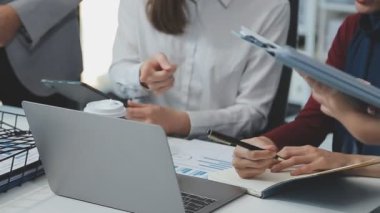 Genç iş uzmanlarından oluşan canlı bir ekip, son teknoloji ürünü bir ofiste etkili bir şekilde iş birliği yaparak finansal stratejiler ve ilkeler sergiliyor.