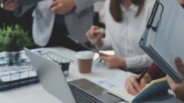 Genç iş uzmanlarından oluşan canlı bir ekip, son teknoloji ürünü bir ofiste etkili bir şekilde iş birliği yaparak finansal stratejiler ve ilkeler sergiliyor.