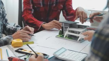 Mühendisler, mühendislik araçları ve inşaat yöntemleri üzerinde yoğunlaşarak, mimari planları incelemek ve tartışmak için bir ofiste bir araya geldiler..