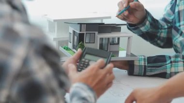 Mühendisler, mühendislik araçları ve inşaat yöntemleri üzerinde yoğunlaşarak, mimari planları incelemek ve tartışmak için bir ofiste bir araya geldiler..