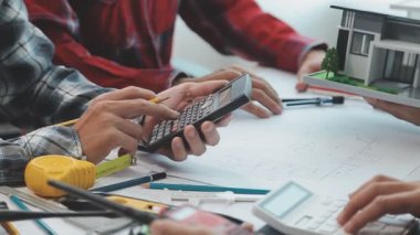 Mühendisler, mühendislik araçları ve inşaat yöntemleri üzerinde yoğunlaşarak, mimari planları incelemek ve tartışmak için bir ofiste bir araya geldiler..