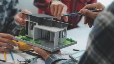 Mühendisler, mühendislik araçları ve inşaat yöntemleri üzerinde yoğunlaşarak, mimari planları incelemek ve tartışmak için bir ofiste bir araya geldiler..