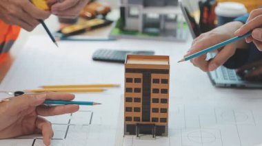 Mühendisler, mühendislik araçları ve inşaat yöntemleri üzerinde yoğunlaşarak, mimari planları incelemek ve tartışmak için bir ofiste bir araya geldiler..